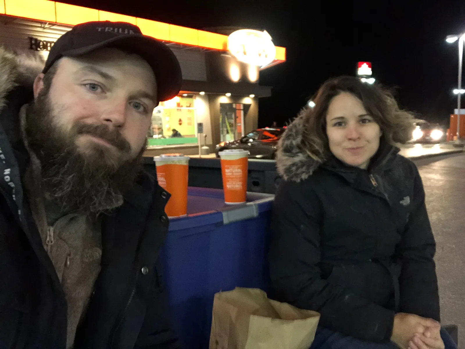 Two stressed out looking people on the back of a truck eating A&W