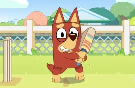 Bandit from Bluey standing at the stumps with a cricket bat, mid-game.