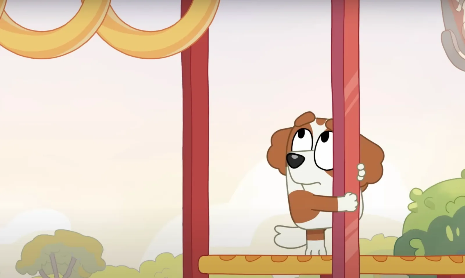 Bentley clasping a pole on the monkey bars, looking at the grab rings that are too far away.