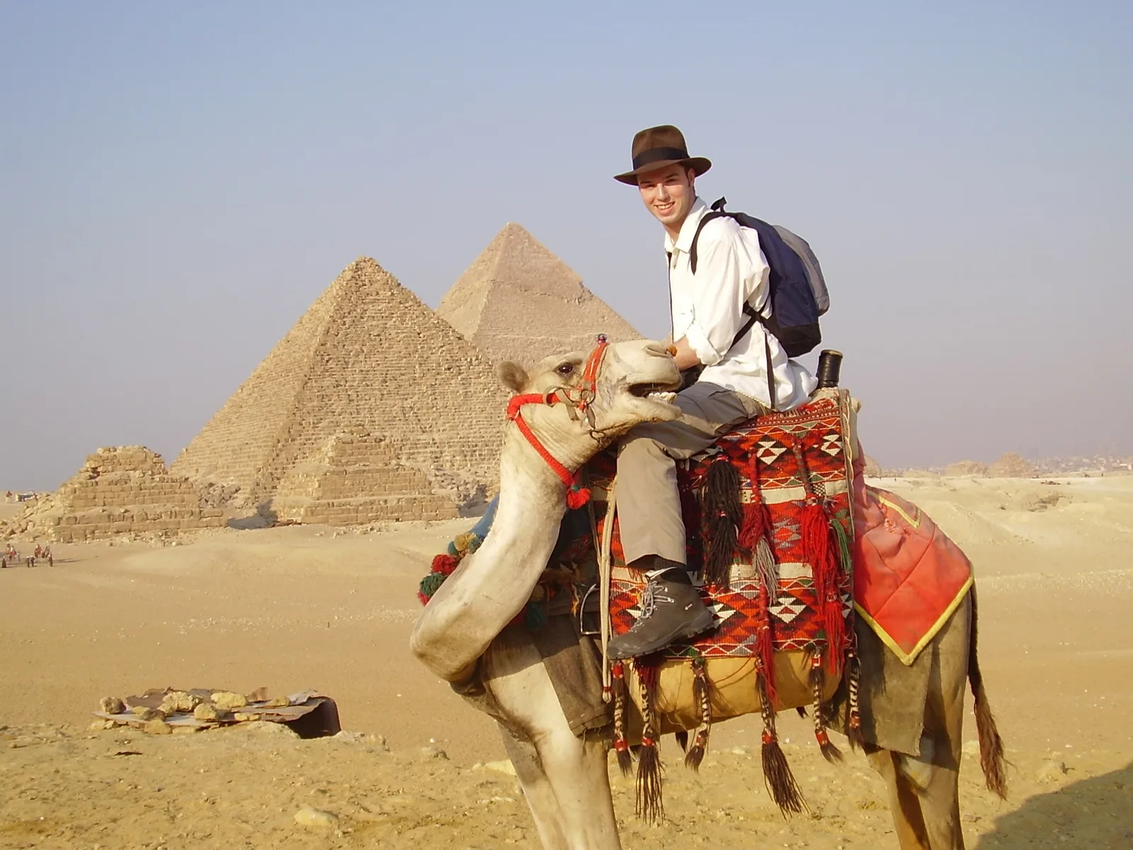 Craig in his adventure hat sitting on a camel outside the Giza Pyramids
